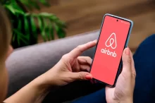 Žena drží v ruce telefon s logem Airbnb.