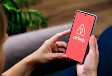 Žena drží v ruce telefon s logem Airbnb.