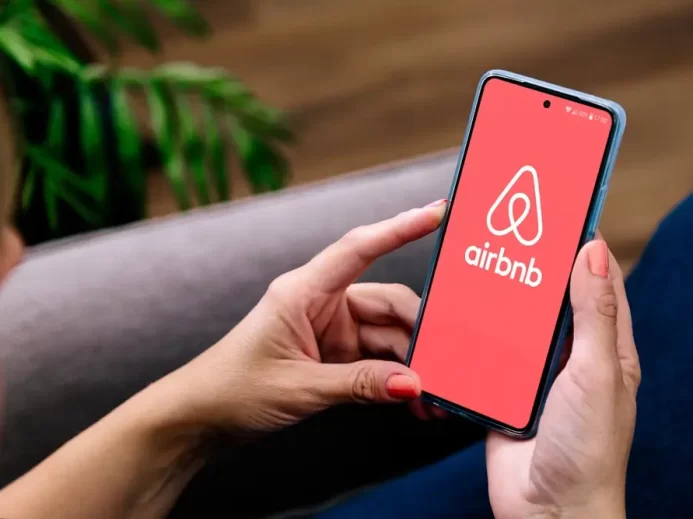 Žena drží v ruce telefon s logem Airbnb.