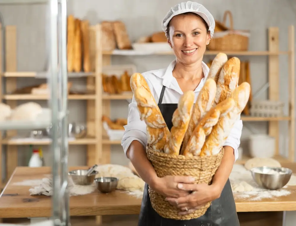shutterstock_2547814923 - Pravda24 Pekařka drží v ruce košík plný pečiva.