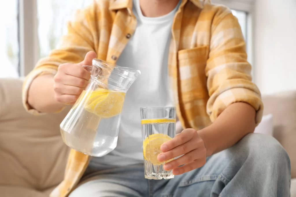 Obyčejná voda s citronem. Zdroj: Shutterstock - Pravda24 Člověk nalévající si vodu s citronem a medem.