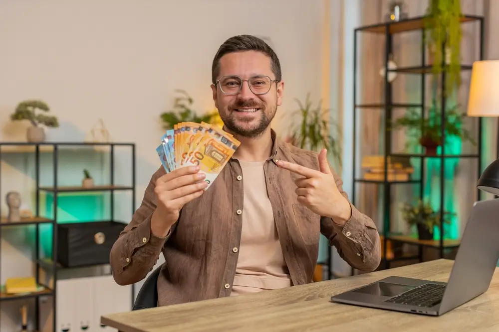shutterstock_2562126133 - Pravda24 Muž drží v ruce peníze.