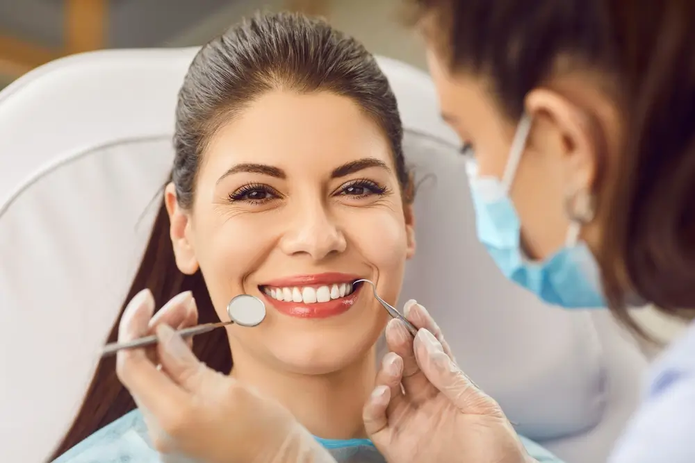 shutterstock_2570358635 - Pravda24 Žena sedí u zubaře na křesle a usmívá se.