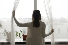 Žena se kouká z okna.