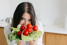 Žena drží v ruce talíř se zeleninou.