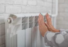 žena si ohřívá ruce u topení