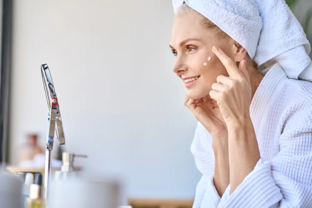 shutterstock_1982566964 - Pravda24 Žena na sebe maže krém.