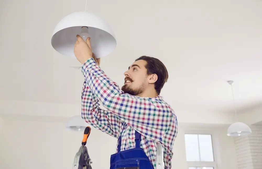 shutterstock_2103186683 - Pravda24 Školník opravuje žárovku.
