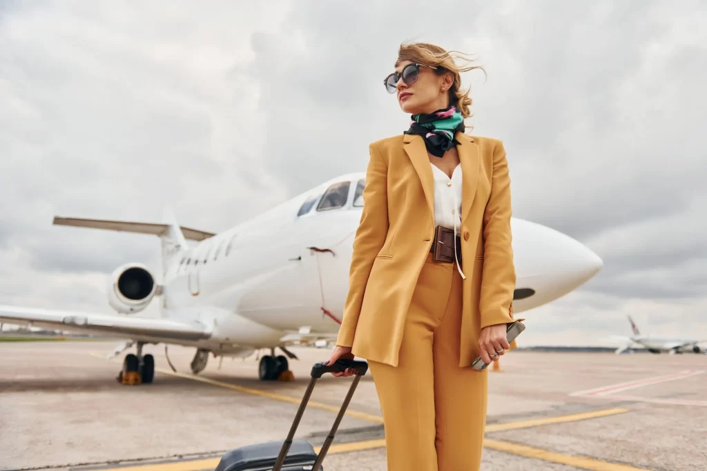Luxus ženy může odhalit jen drobný detail. Zdroj: Shutterstock - Pravda24 Luxusně oblečená žena s kufrem před letadlem.