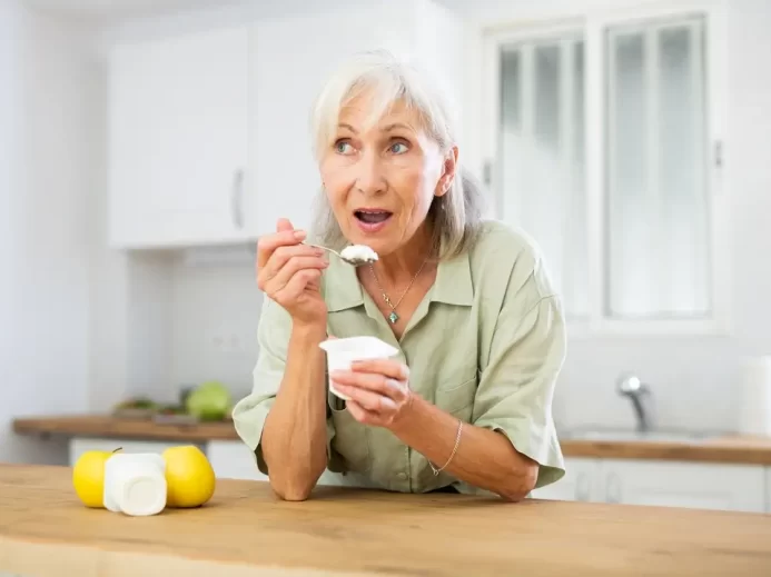 Žena konzumuje jogurt.
