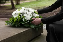žena pokládá věnec na hrob