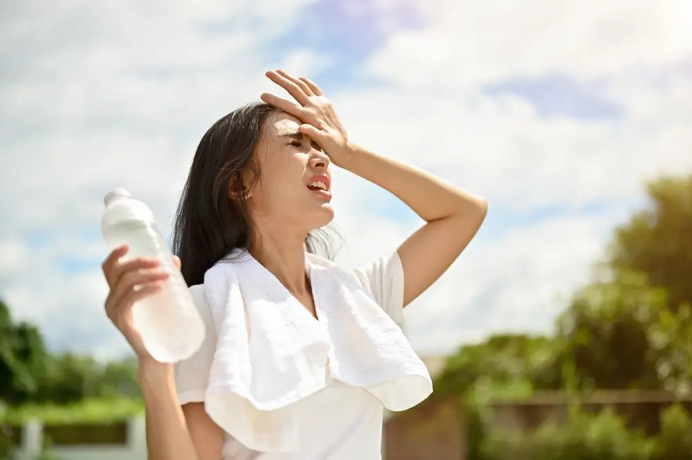 shutterstock_2331520895 - Pravda24 Mladá žena se drží za zpocené čelo.