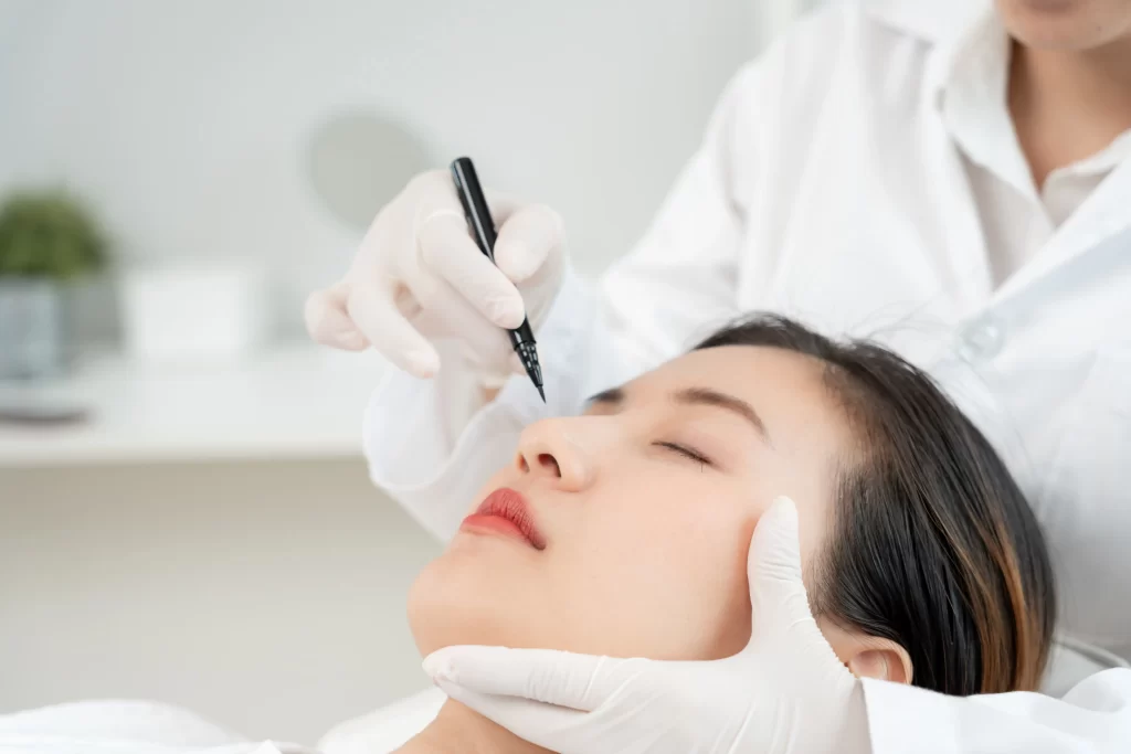 Plat plastického chirurga je zpravidla několikanásobně vyšší. Zdroj: Shutterstock - Pravda24 Lékařka malující na obličej své pacientky před plastickou operací.