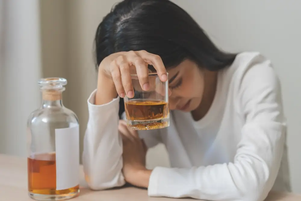 shutterstock_2390637083 - Pravda24 Žena pije alkohol a vypadá sklesle.