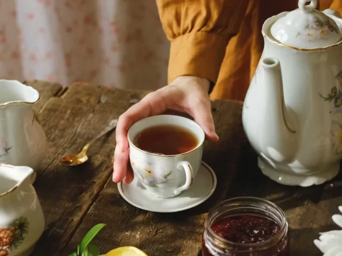 žena nalévá čaj z porcelánové konvice