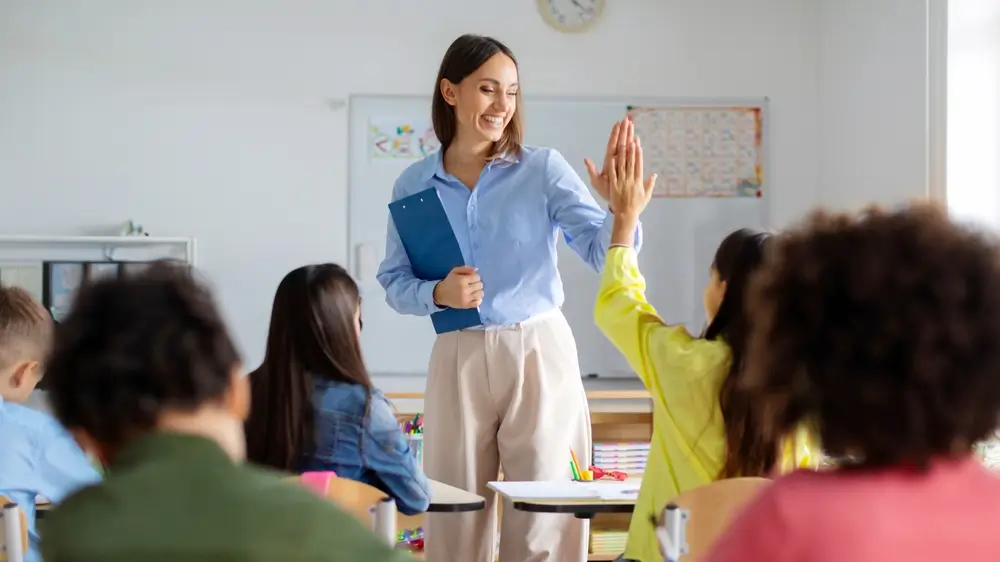 shutterstock_2471109121 - Pravda24 Učitelka se usmívá a plácá si s žákyní.