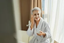 Starší žena používá zkrášlovací přípravek.
