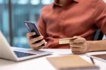 Muž drží v ruce mobilní telefon a kartu.