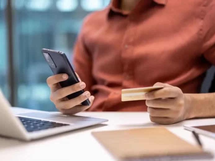 Muž drží v ruce mobilní telefon a kartu.