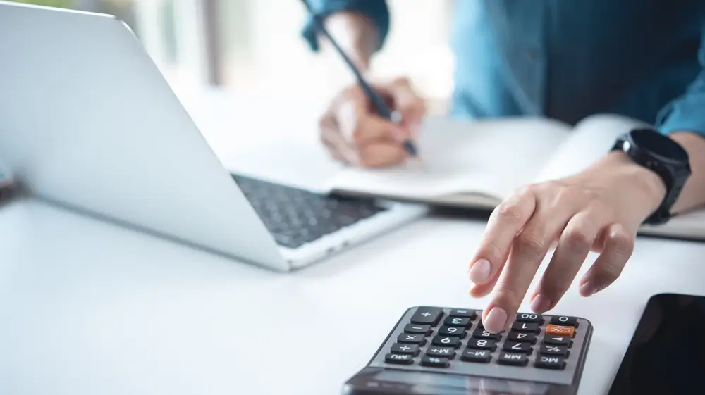 shutterstock_2505050815 - Pravda24 Muž kalkuluje a zapisuje si výpočty do sešitu.