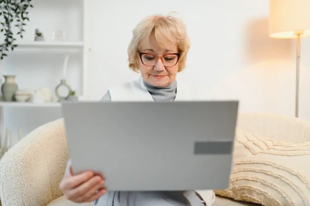 shutterstock_2572252159 - Pravda24 Starší žena hledá něco na notebooku.