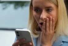 Žena udiveně hledí do mobilu.