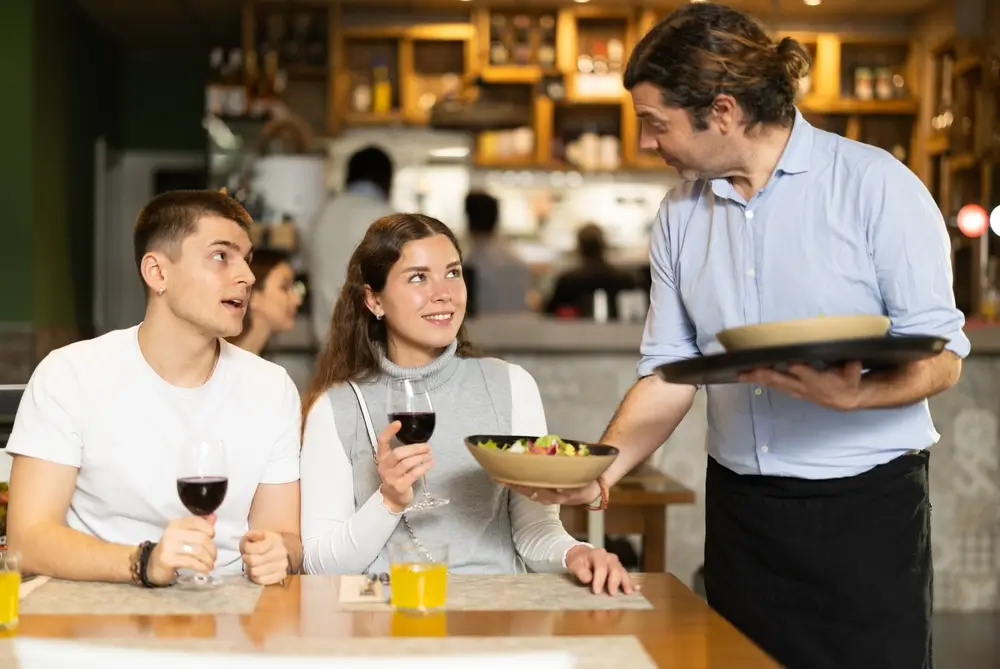 shutterstock_2594469611 - Pravda24 Číšník mluví k hostům.