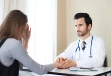 Doktor drží ženu za ruce na znamení podpory.