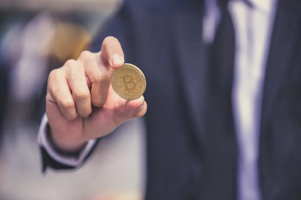 shutterstock_792732790 - Pravda24 Muž drží v ruce minci se znakem bitcoinu.