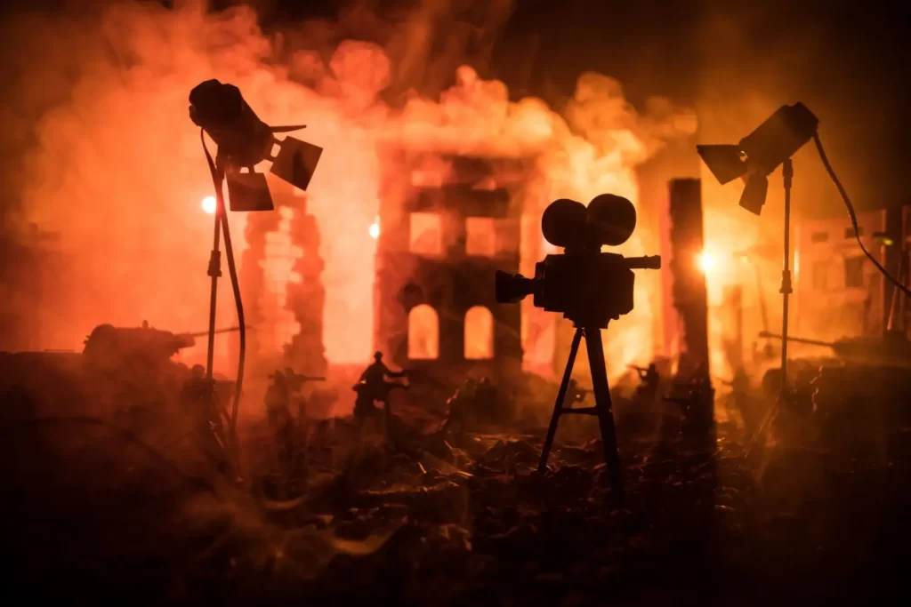 - Pravda24 Silueta filmové kamery a reflektorů před hořícím městem, evokující zmatek a paniku, kterou vyvolala rozhlasová adaptace Války světů