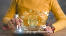Žena pracuje s tabletem, na kterém se zobrazuje 3D mapa obličeje a bezpečnostní ikony související s deepfake