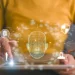 Žena pracuje s tabletem, na kterém se zobrazuje 3D mapa obličeje a bezpečnostní ikony související s deepfake