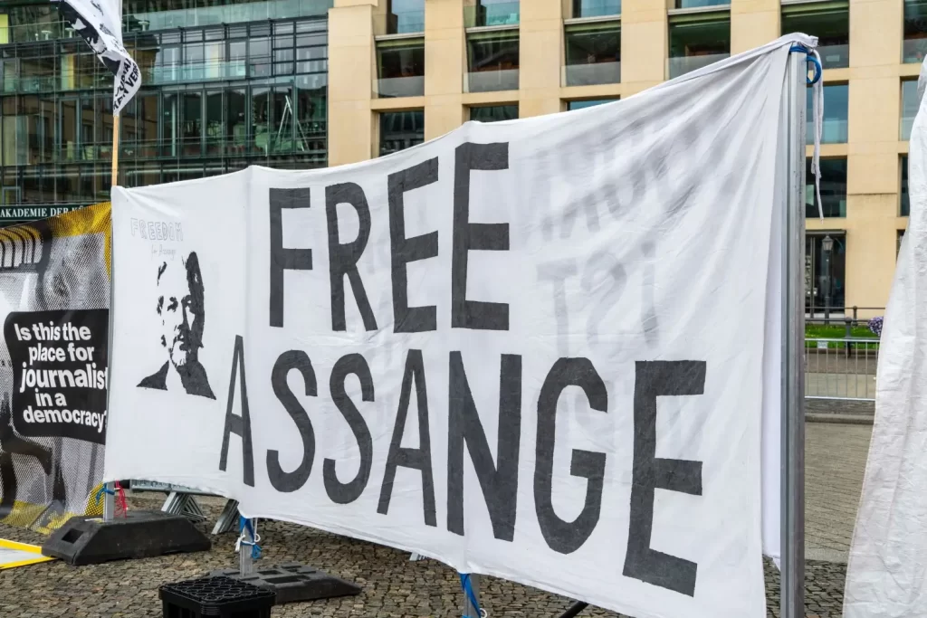 - Pravda24 Velký bílý transparent s nápisem „Free Assange“ rozvěšený během veřejného protestu za svobodu slova a podporu Juliana Assange ve veřejném prostoru