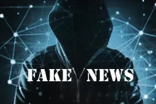 Temná postava v kapuci na pozadí digitální sítě s nápisem "Fake News"