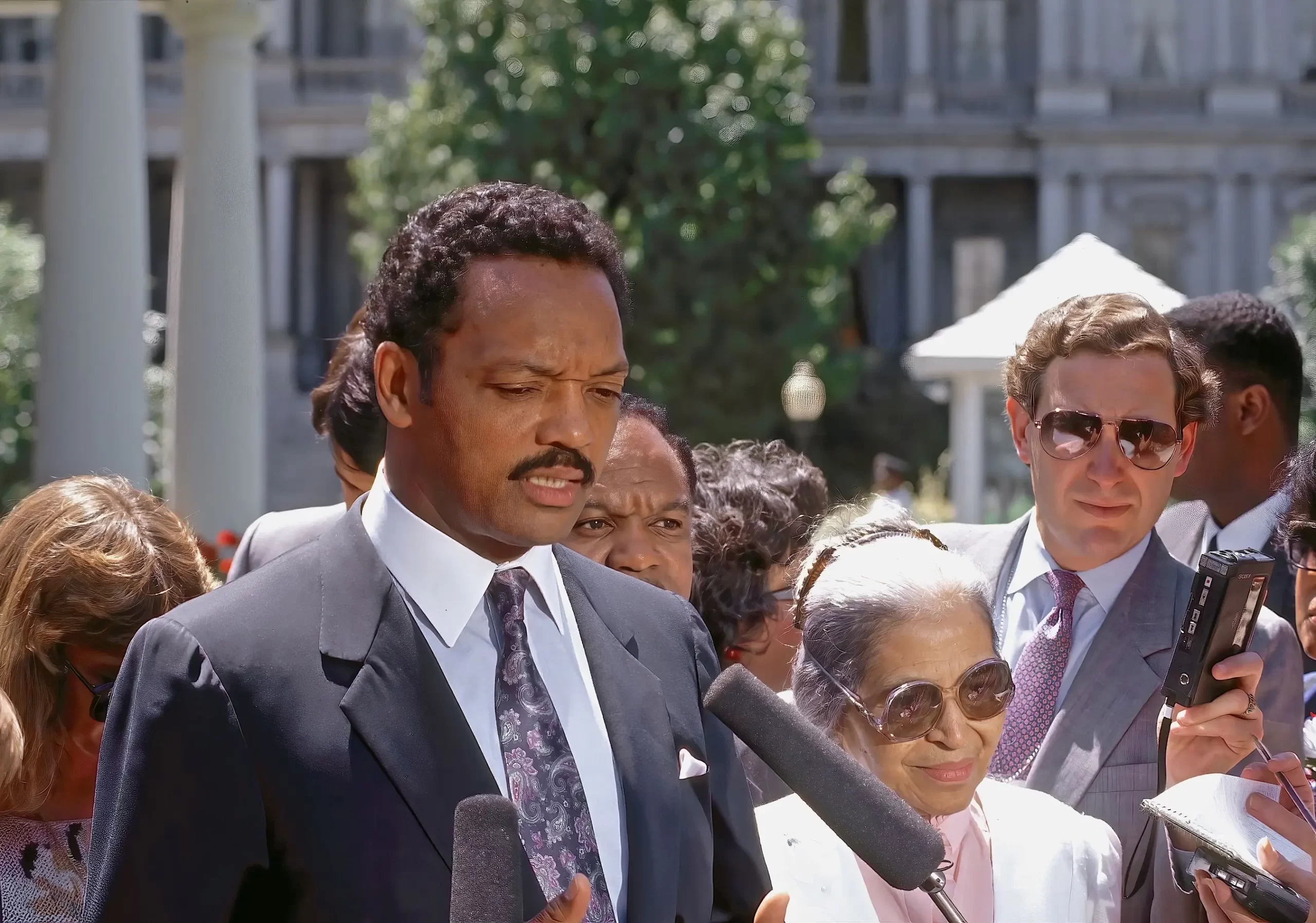 - Pravda24 Reverend Jesse Jackson hovoří s novináři na příjezdové cestě k západnímu křídlu Bílého domu Vedle něj stojí Rosa Parksová