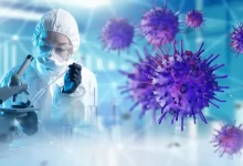 Laboratorní pracovnice v ochranném obleku pracuje s mikroskopem