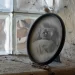 Zašlá oválná fotografie muže na smrtelné posteli, postavená na zaprášeném parapetu