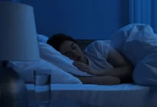 Žena klidně spící v posteli při tlumeném měsíčním světle v pokoji