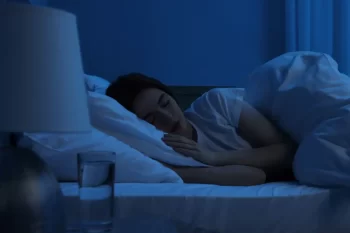 Žena klidně spící v posteli při tlumeném měsíčním světle v pokoji