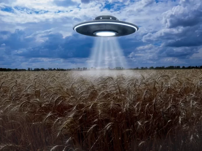 Ilustrace létajícího talíře nad obilným polem, inspirovaná fenoménem kruhů v obilí a častými popisy pozorování UFO na venkově