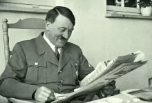Adolf Hitler sedící v křesle při čtení novin