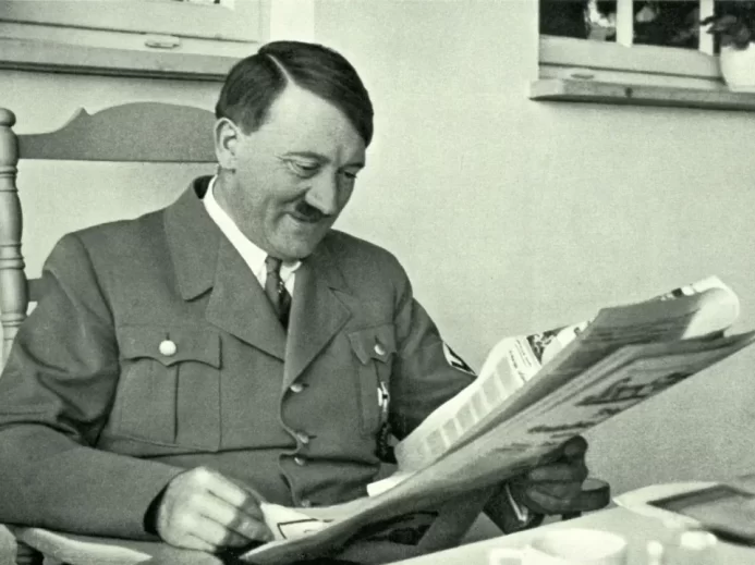 Adolf Hitler sedící v křesle při čtení novin