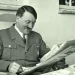 Adolf Hitler sedící v křesle při čtení novin