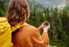 Turistka s batohem drží kompas při cestě přírodou
