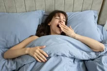Zívající žena ležící v posteli
