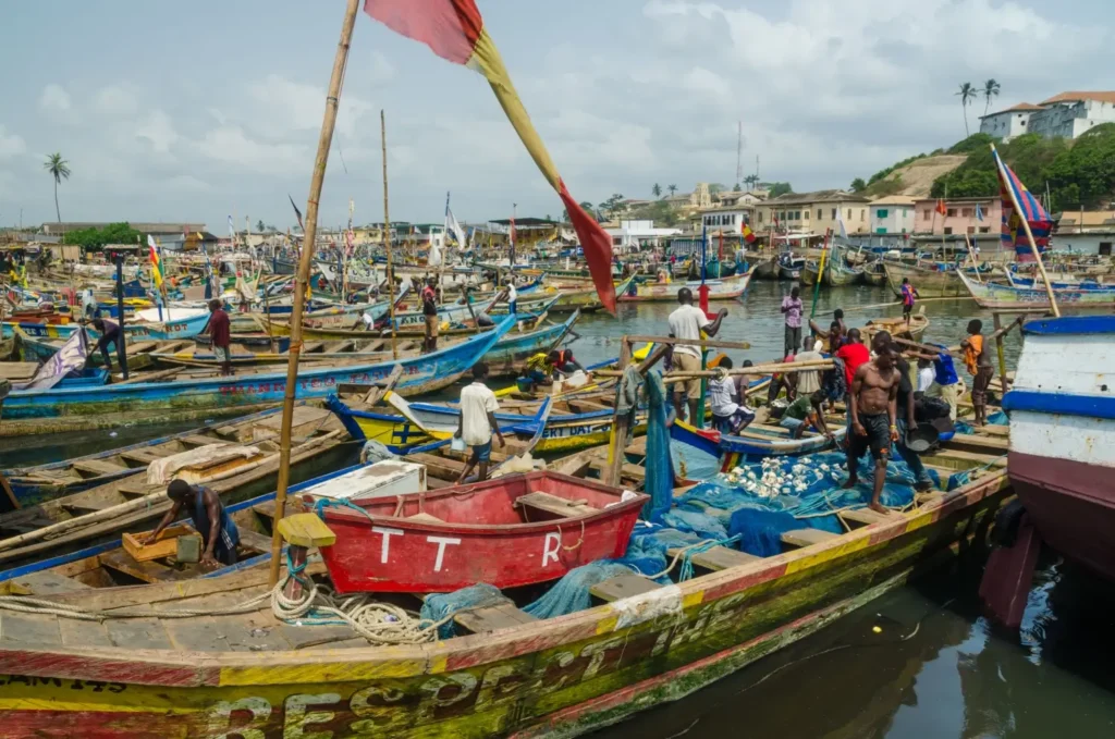 Barevné rybářské čluny zakotvené v rušném přístavu Cape Coast, Ghana