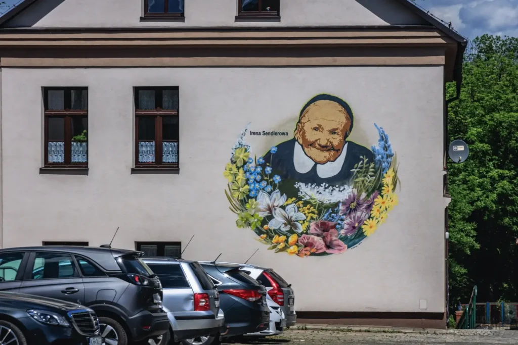Nástěnná malba Ireny Sendlerové s květinovým rámem na domě v Polsku