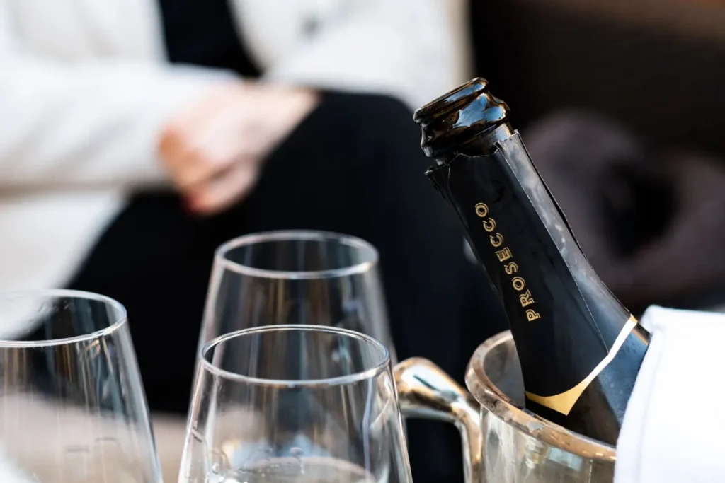 - Pravda24 Detail láhve prosecca v chladícím kbelíku se sklenicemi připravenými k nalití