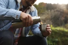 Mladý muž si nalévá horký nápoj z termosky