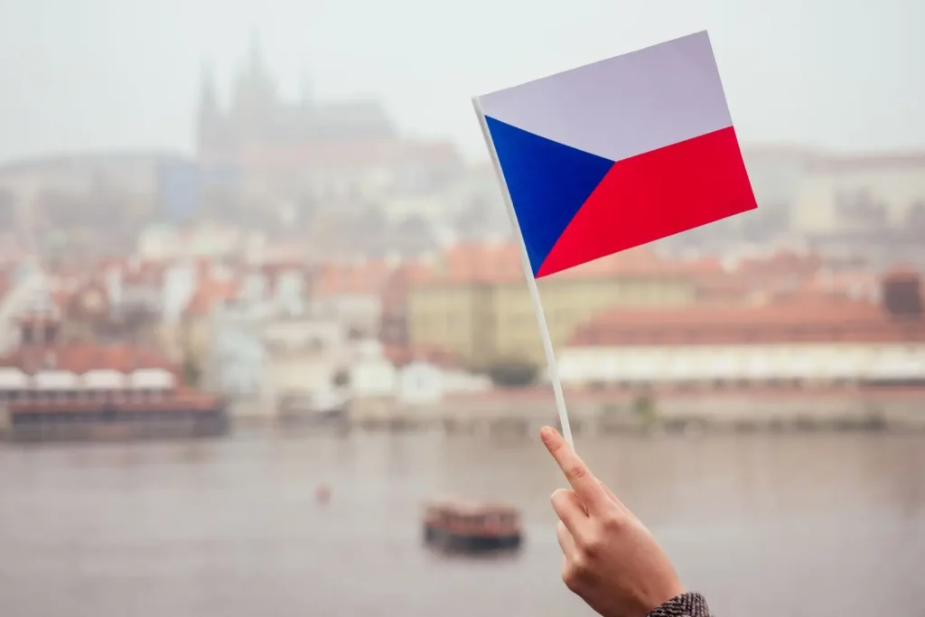 Ruka držící českou vlajku nad Prahou